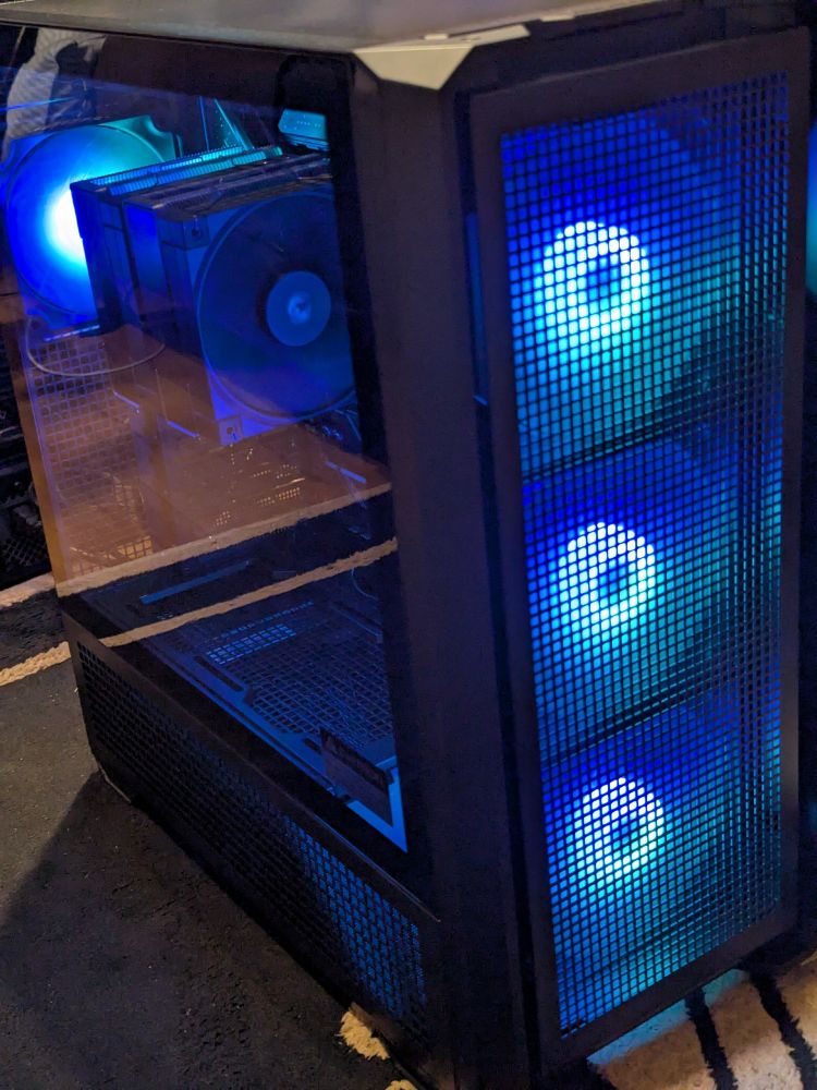 デスクトップPC(格子状のフィルター越しに正面の大きなケースファン3つがLEDで青く光っている)