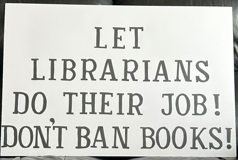 Photo of a protest sign which reads: Let Librarians do their Job! Don’t Ban Books!. The lettering is black and in a large font. The background of the sign is white