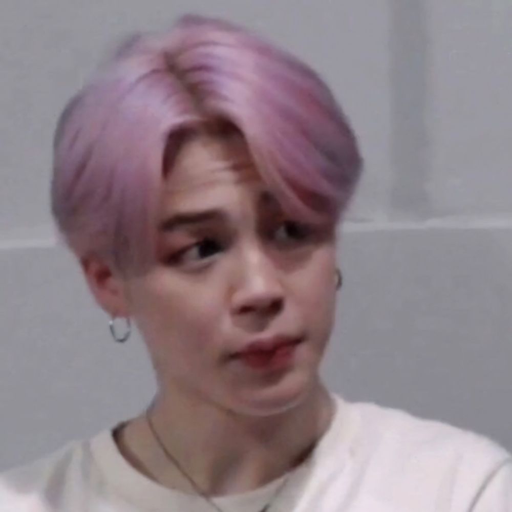Jimin with pastel pink hair, wearing a white shirt