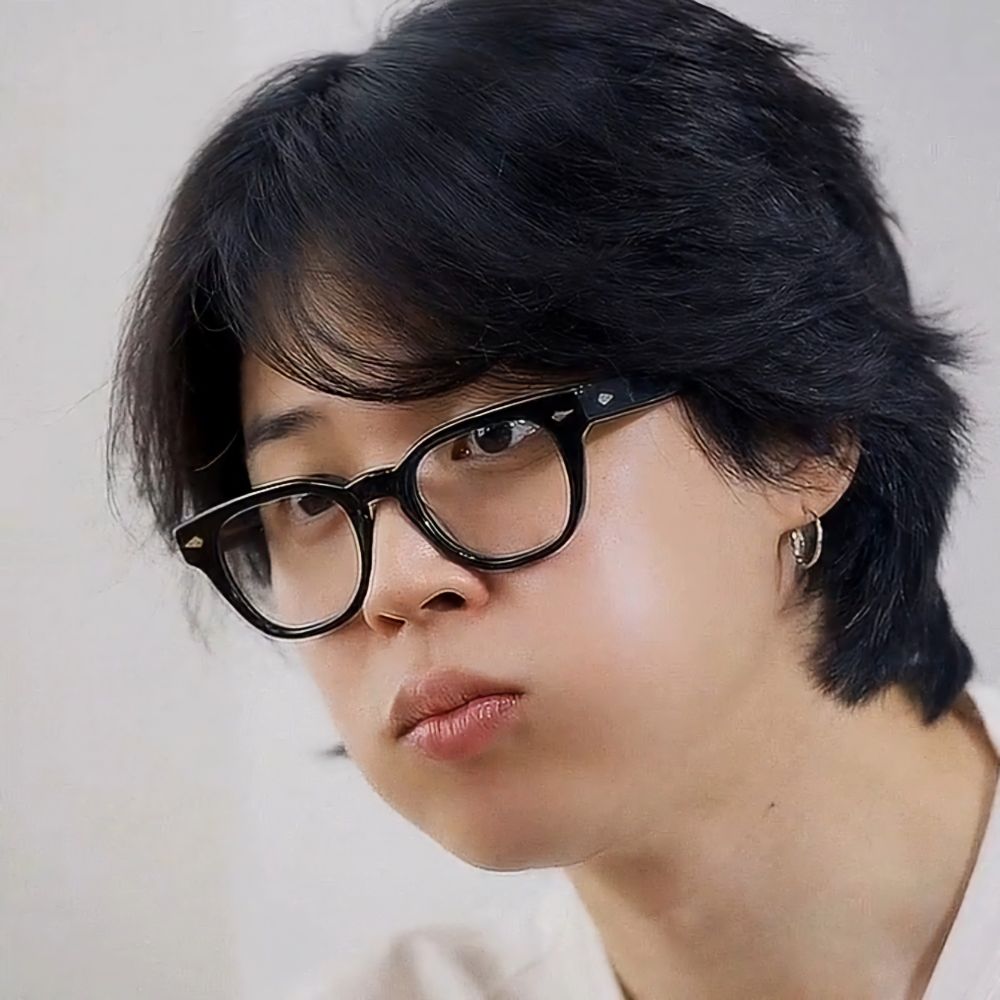 Jimin with dark hair is wearing glasses with a black frame