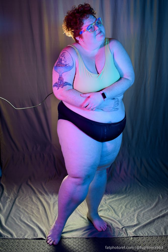 A fat woman in underwear with purple and blue lighting 