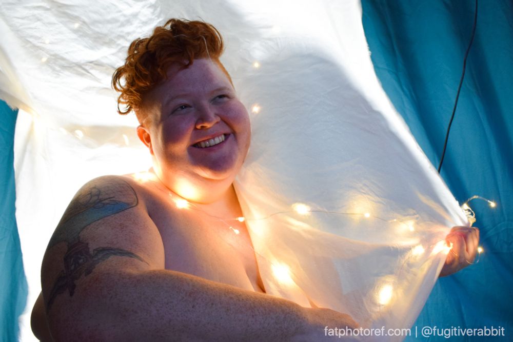 A fat woman from the bust up with white twinkle lights