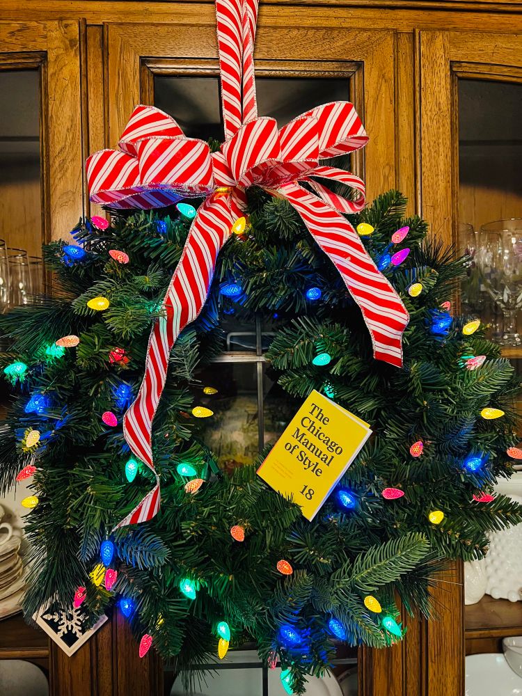A minibook of The Chicago Manual of Style inside a lit holiday wreath