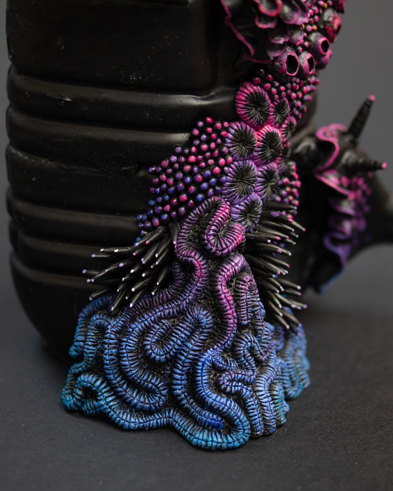Nudibranches and coral reef sculptures on a black plastic bottle. The slugs and reef are also painted in black as a base and adorned with rainbow colors.