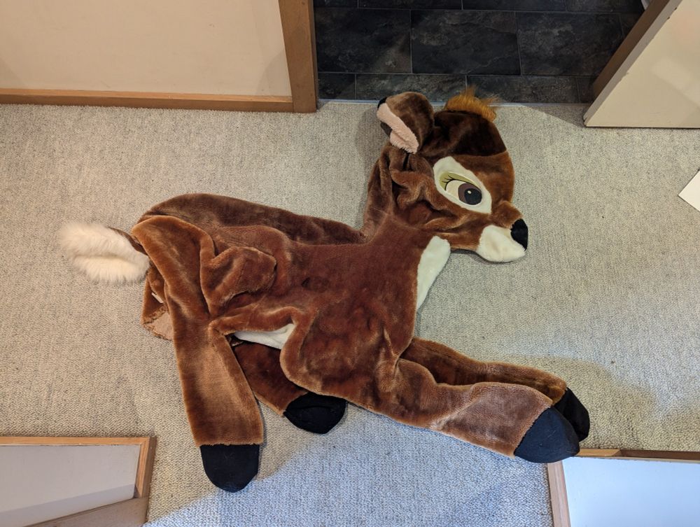 Large unstuffed Bambi plush laying on the floor. 