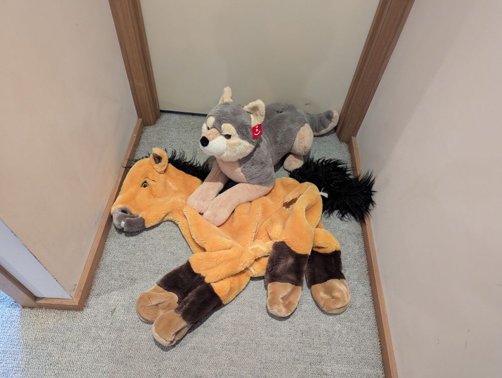 Aurora wolf plush and an unstuffed, jumbo Spirit Stallion of the Cimarron horse plush laying on the floor. 