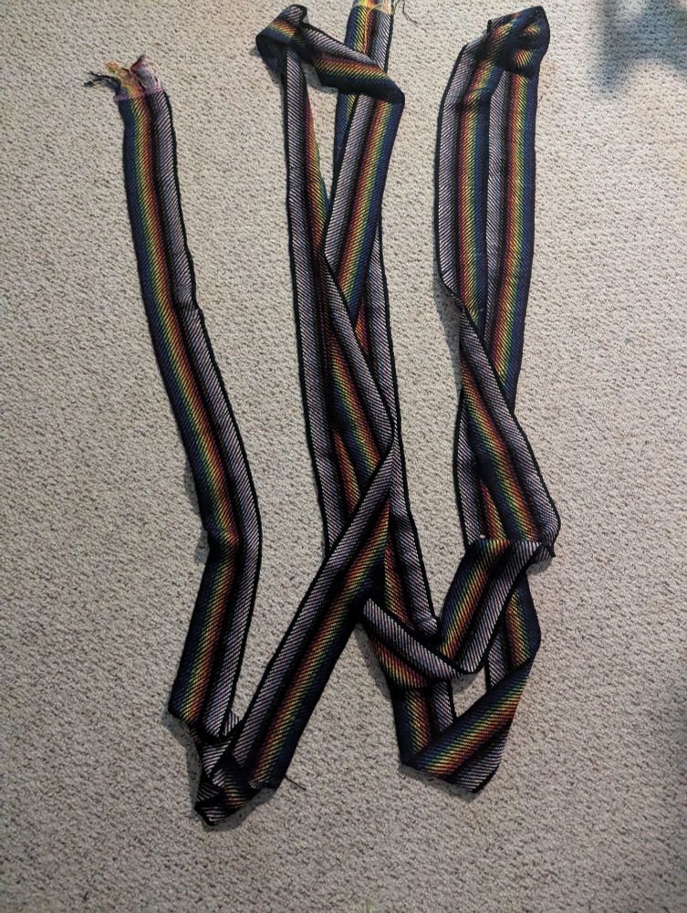 A continuous length of rainbow striped fabric laid out like a "W" to show about 30 ft of fabric in one image (background is an oatmeal colored berber carpet)