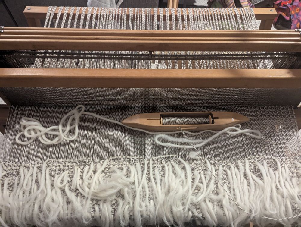 White pencil roving strands of tied into weaving of white/brown plied wool yarn.