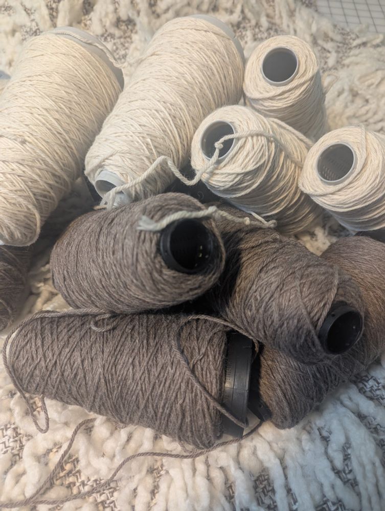 Cones of white and brown wool on a handwoven wrap.