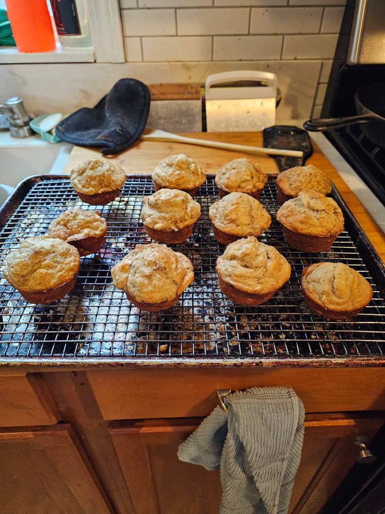 Twelve banana nut muffins resting on a wire rack.
