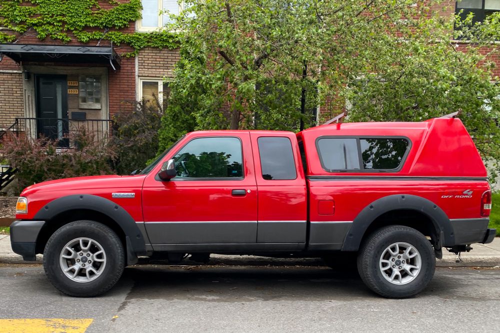 Red Ford Ranger pickup truck against some green shrubbery. Eastern Montreal. I just want a small truck dammit!