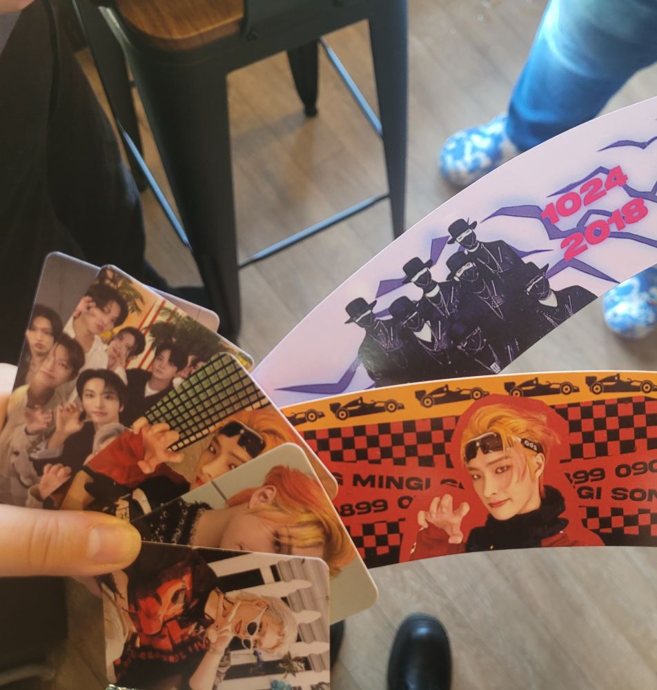 user holding fanmade photocards and cup sleeves of ateez