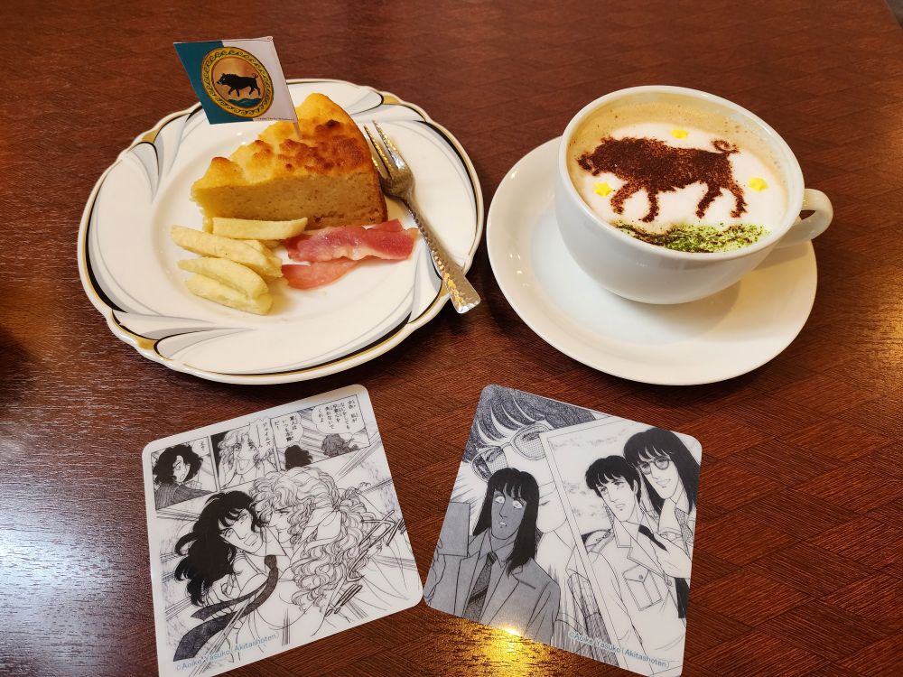 弥生美術館前喫茶港やの青池保子展コラボメニュー
エーベルバッハ少佐のカプチーノ＆カルトフェルトルテ
コラボメニューのオマケのコースター（エロイカより愛をこめて　よりシーン抜粋図柄）