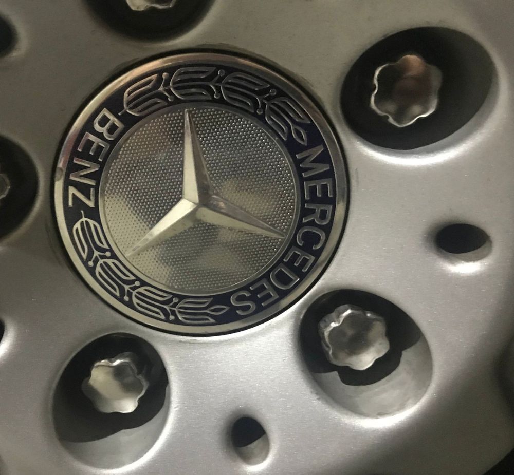 Image of Mercedes-Benz flower lug nuts with chrome caps. Except these ones are clean and new... not twisted, bent, falling off, or jammed into your socket with determination.