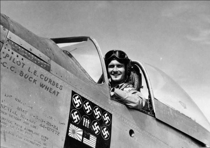 Picture denotes an American pilot in the cockpit of a plane with painted symbols showing how many air victories the pilot has