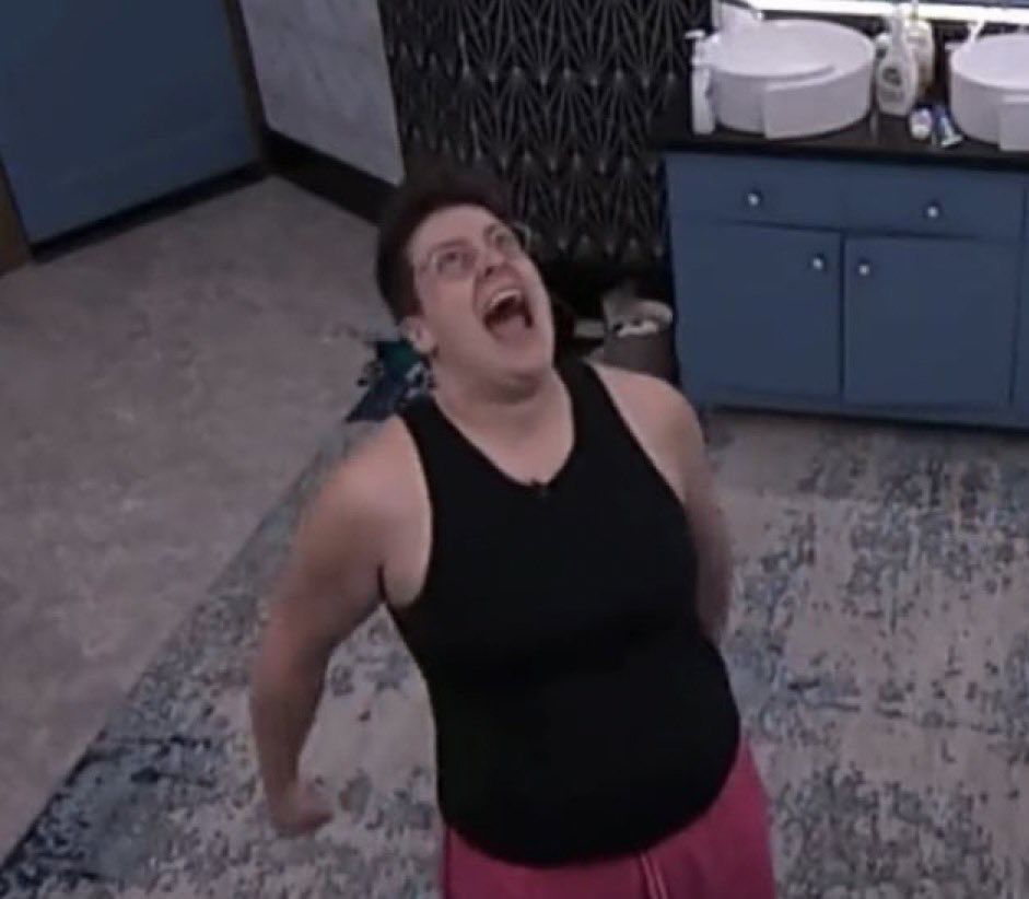 izzy standing in the bb25 bathroom with her arms pulled back behind her slightly while she looks up at the ceiling and screams excitedly