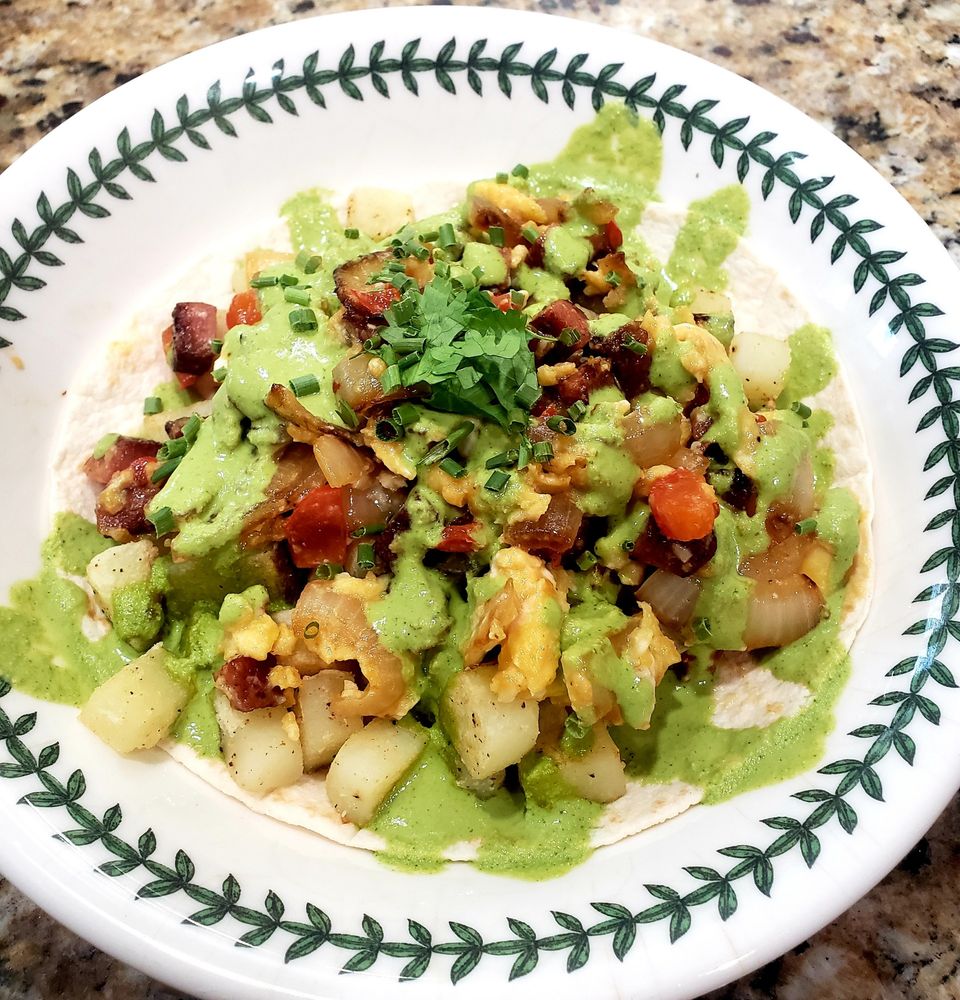 A bowl featuring the open-face burrito and drizzled with sauce