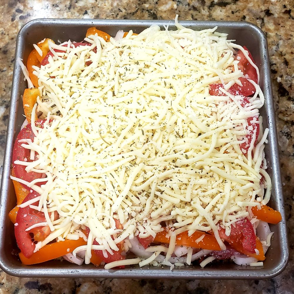 Raw pizza dough with toppings in a square pan before baking.