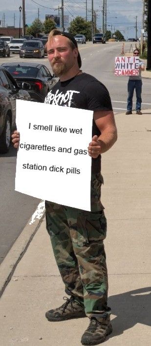 An image of Benjamin Stanton wearing a Slipknot t-shirt and camo pants. He's holding a sign that's been edited to read 