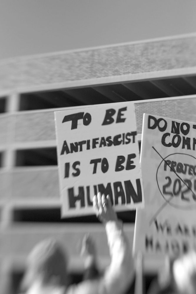 No Kings rally sign in black and white that says TO BE ANTIFASCIST IS TO BE HUMAN. 