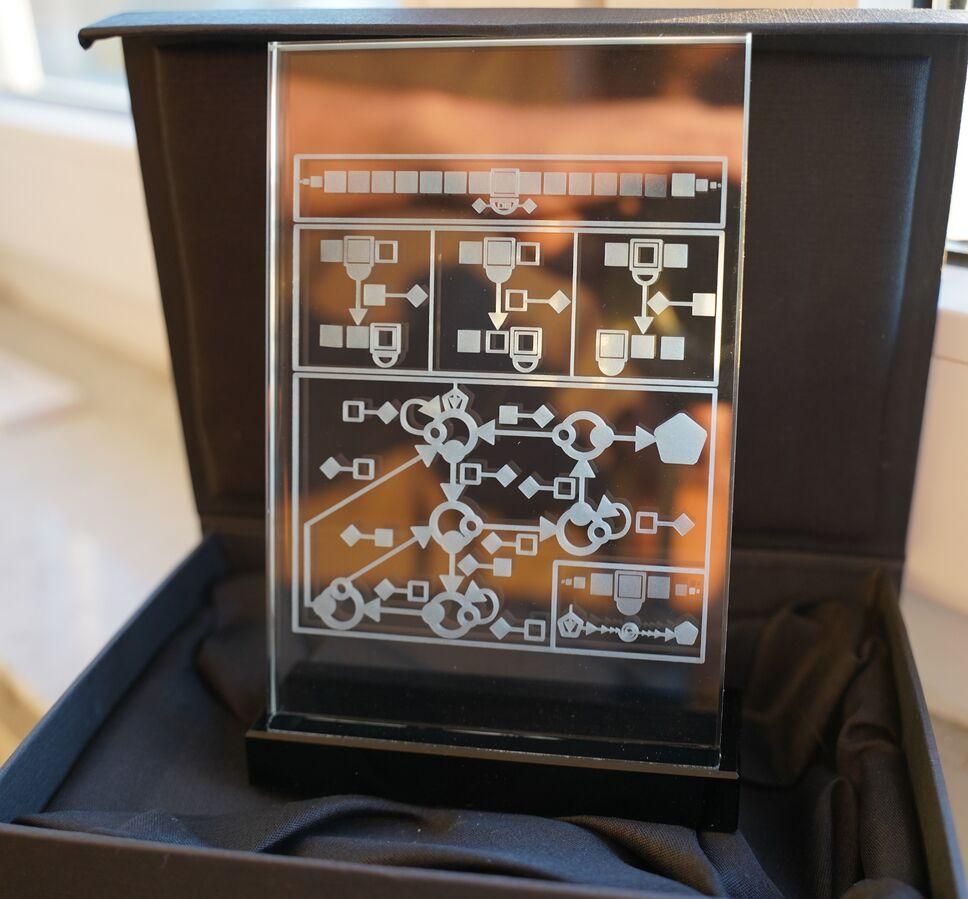 A copper plaque engraved with rather cryptic symbols indicating a Turing machine.  This is the tropy to be awarded to the first person or group who is first acknowledged by the bbchallenge.org community to have resolved the Antihydra problem:

https://wiki.bbchallenge.org/wiki/File:Antihydra_award.jpg
