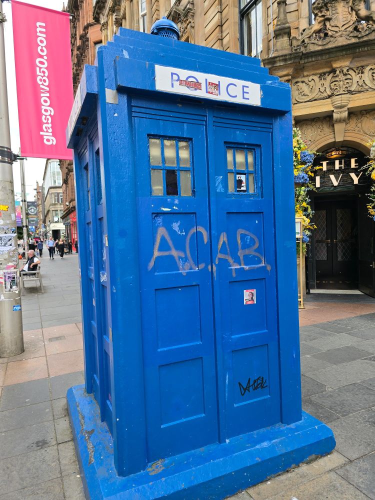 A battered old police box spray painted with the acronym ACAB on Buchanan Street in Glasgow
