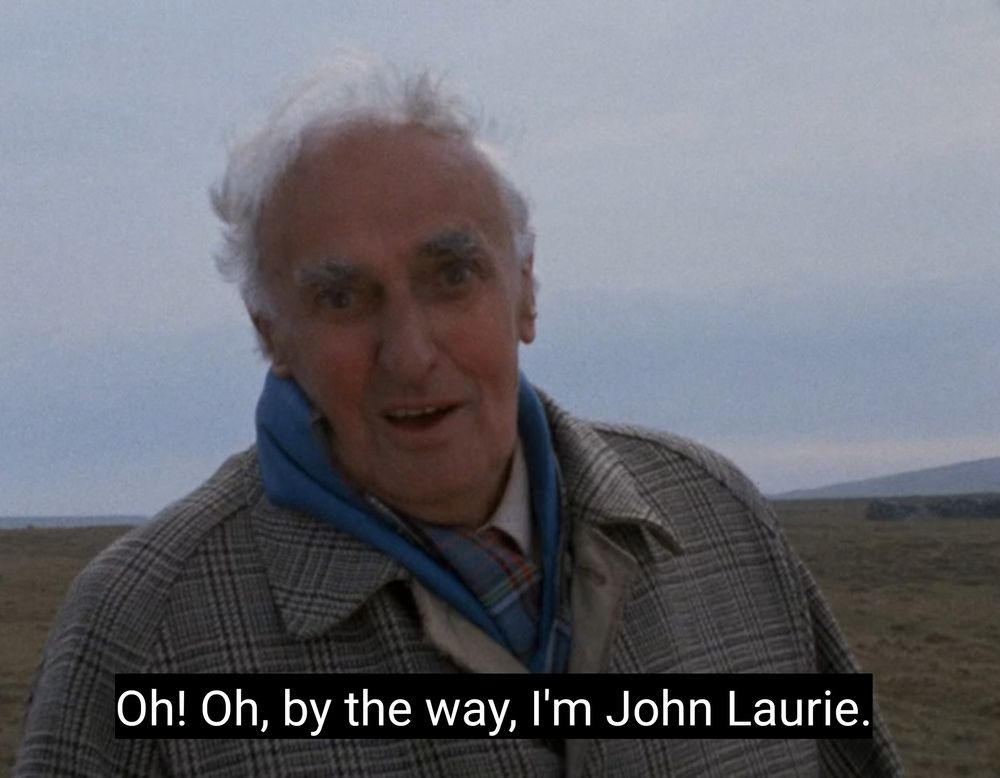 The actor John Laurie on the isle of Foula in Shetland, windswept in a big boat and blue scarf he looks at the camera and says "Oh! Oh by the way, I'm John Laurie"