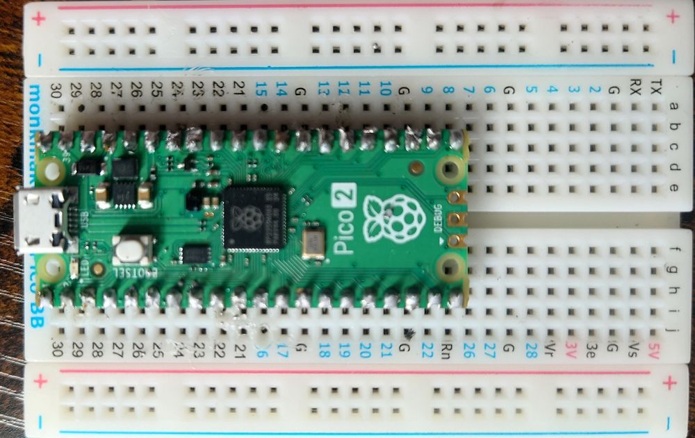 A raspberry pi Pico 2 is set into a mangled breadboard