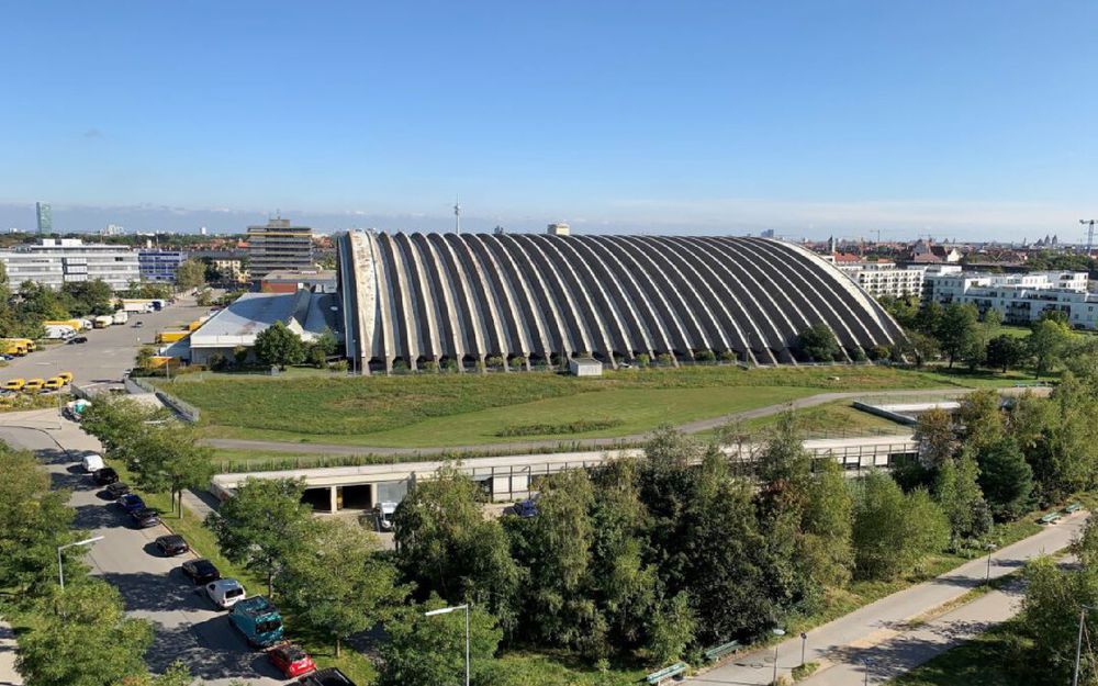 Man sieht die Paketposthalle in München aus der Vogelperspektive. Die Halle mit ihrem ikonischen Rippendach aus Beton steht unter Denkmalschutz.