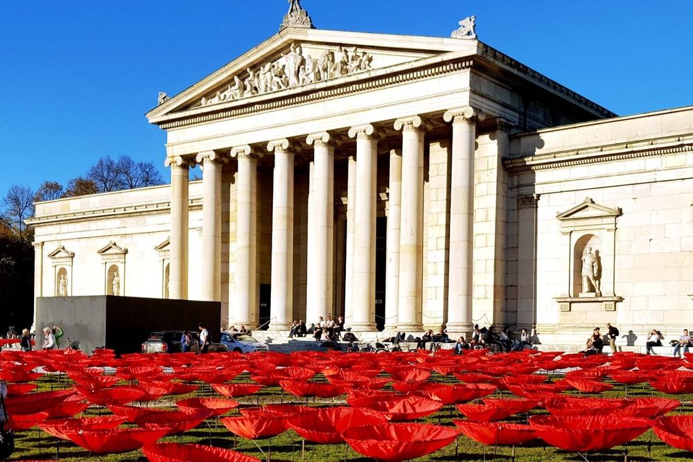 Zu sehen ist die Glyptothek am Münchner Königsplatz. Davor sind tausende stilisierte Mohnblumen aus Stoff zu sehen, die im Rahmen einer Kunstaktion zum 100. Jahrestag des Endes des 1. Weltkrieges 2018 aufgestellt wurden.