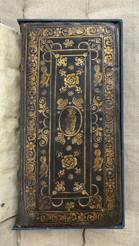 A high decorative gold tooled binding with a Madonna and Child in the centre.
