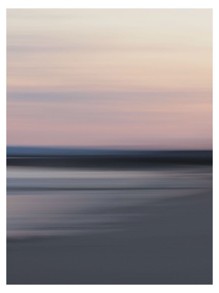 A pink sky and pale to dark bluish grey and black lines from the sea and beach, from intentional camera movement.