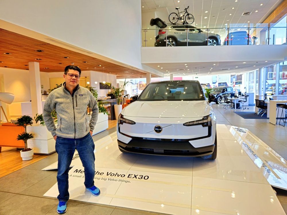 Man standing next to a Volvo electric vehicle branded EX30