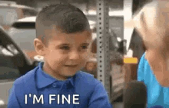 a little boy in a blue shirt is talking to a woman in a parking lot .