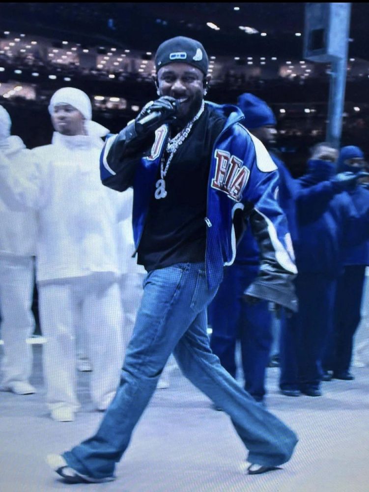 Kendrick Lamar at the Super Bowl halftime show smiling at the camera