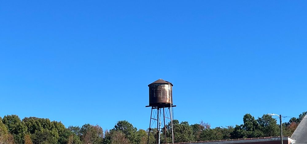 An old rusty water tower is seen contrasted against the clear blue sky.