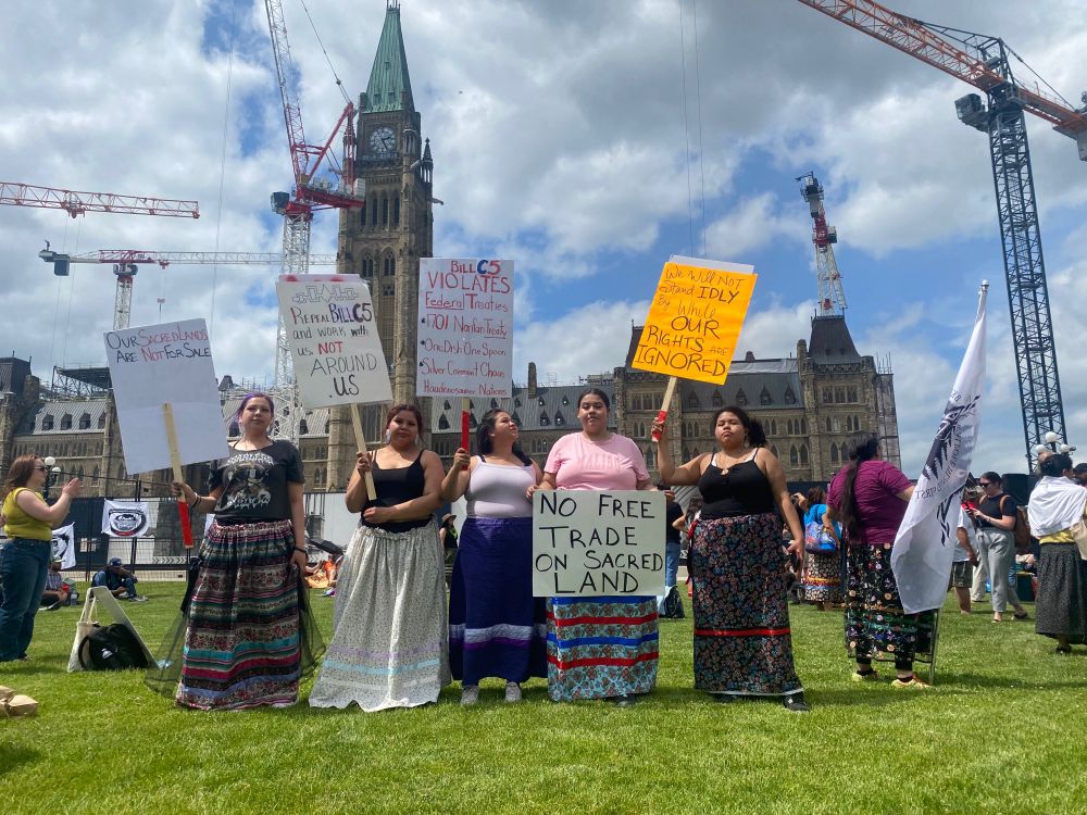 Five young Anishinaabekwe stand with Stop Bill C5 signs in front of the Parliament in Ottawa