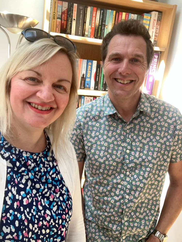 Jo and Chris stand in front of a book case