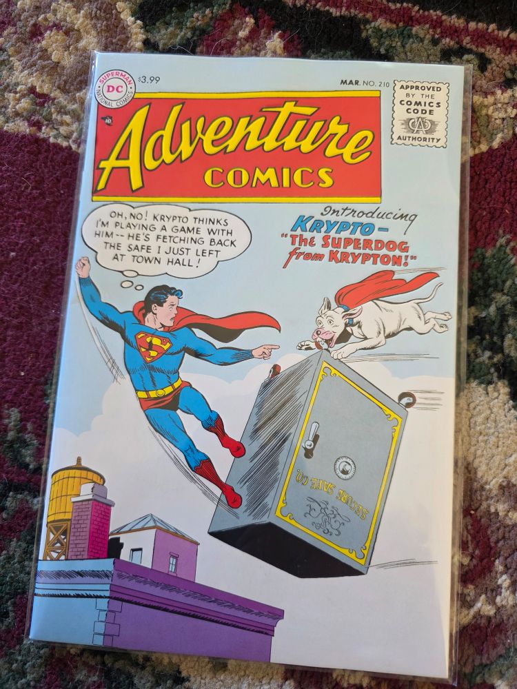 The cover of Adventure Comics 210 featuring Superboy and Krypto the Superdog. The thought Ballon has Superboy thinking "Oh no!  Krypto thinks I'm playing a game with him--he's fetching the safe I  just left at town hall!"  Krypto is flying back to Superboy carrying a large safe in his mouth. 