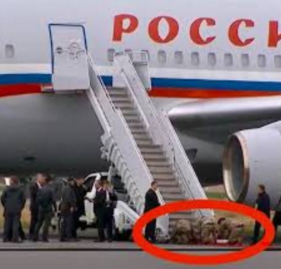 The image shows Trump making US soldiers get on their knees to put a red carpet out for terrorist murderer Vladimir Putin.