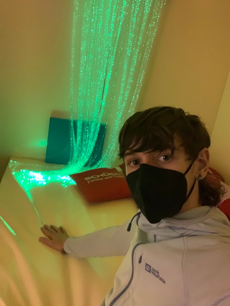 Jason liegt auf einem Wasserbett mit Kissen und grünen Lichterketten 