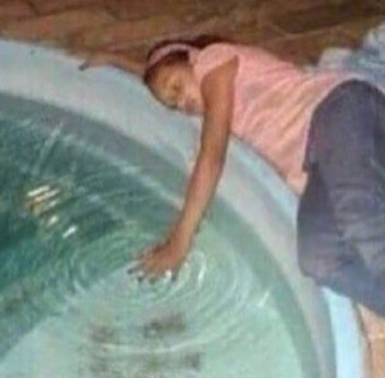 Girl laying down by pool with one hand skimming the water, sadly 
