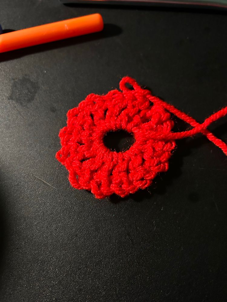 Red yarn crocheted into a magic circle.