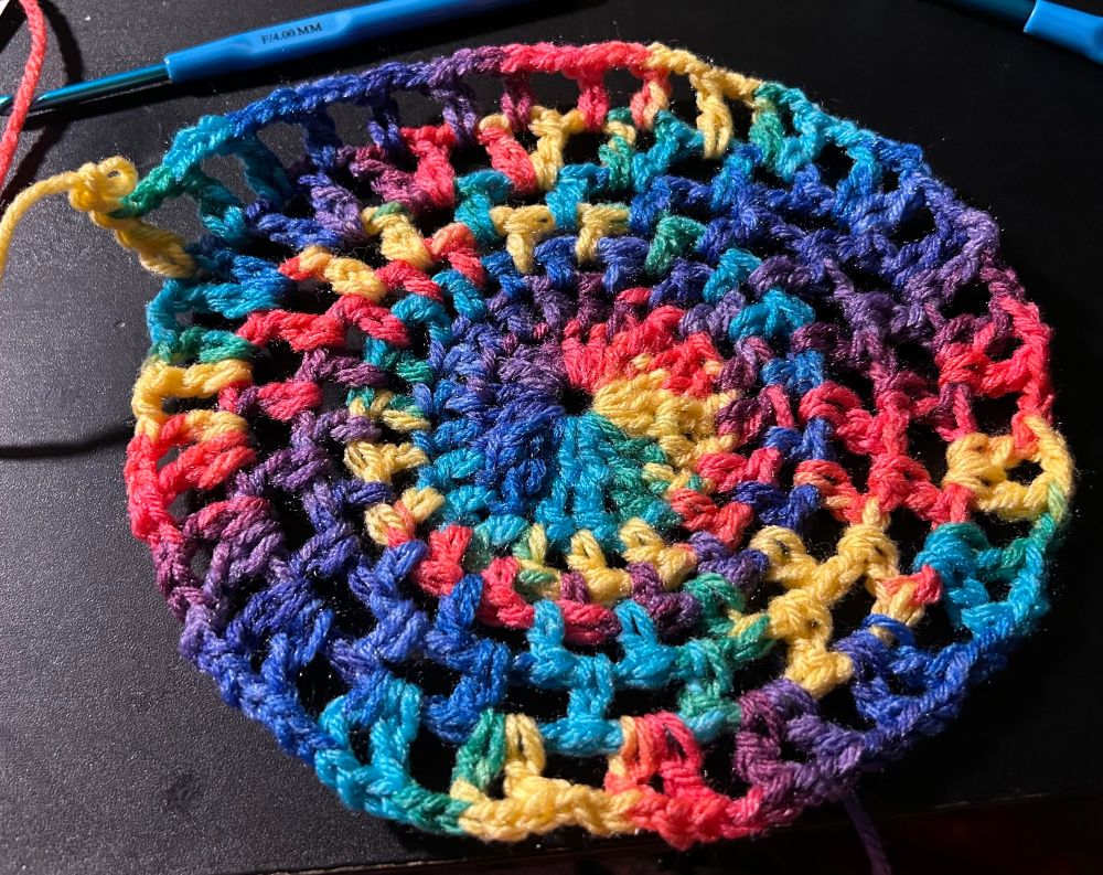 Rainbow yarn woven into a magic circle using a 4.0 mm crochet hook.