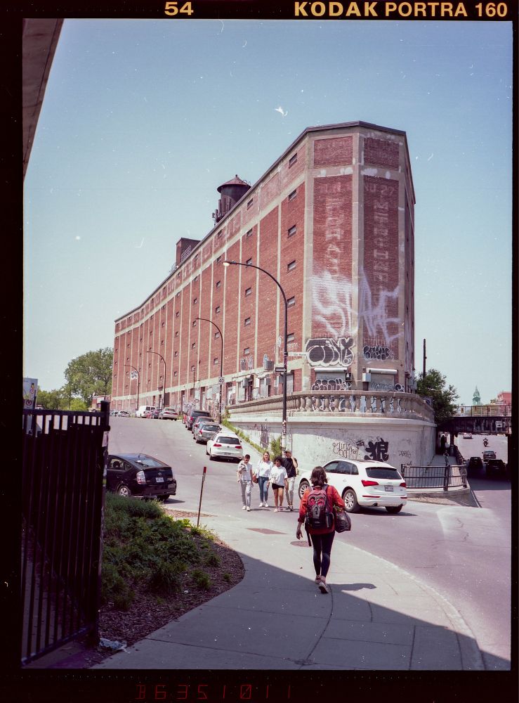 A photo of a large building in Montreal on the intersection of St Laurent and Van Horne. A person is crossing the street in front of the building.