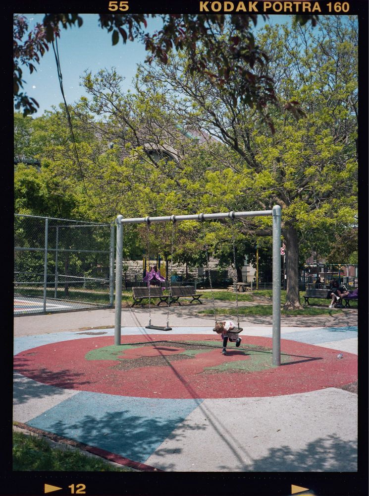 A young girl on a swing in a park in Montreal.