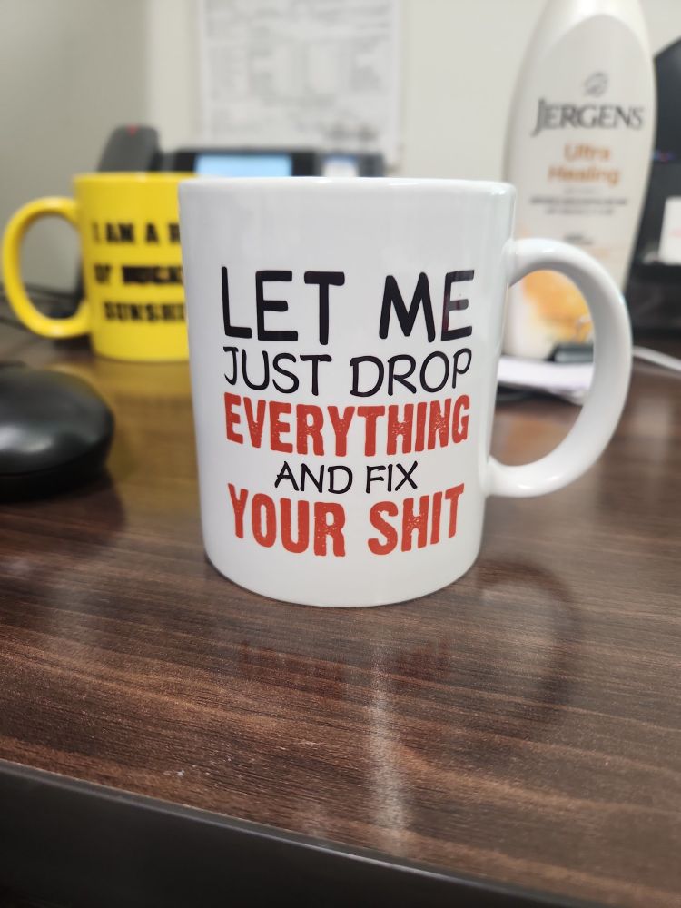A sarcastic coffee mug with the text "Let me just drop everything and fix your shit"