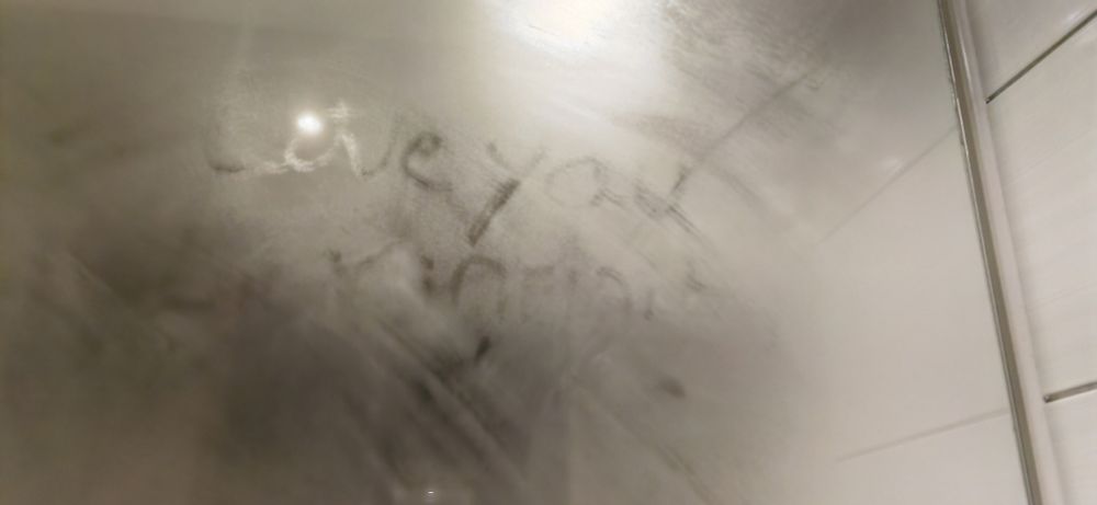 A photograph of a bathroom mirror. Someone has written "Love you, Big yin *unreadable script*". This appeared after my shower on day 2, but not after my shower on day 1. Room's haunted.