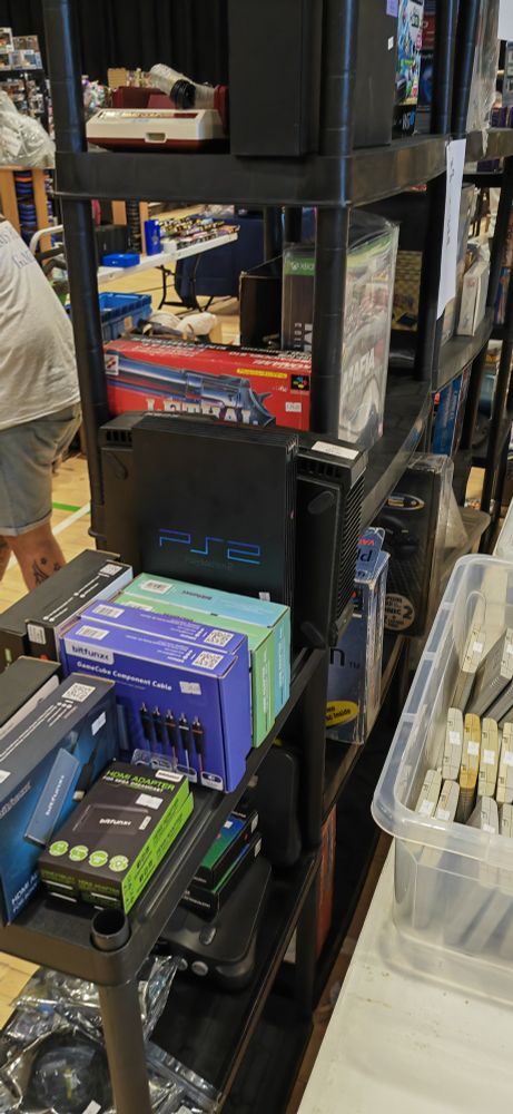 A photograph of some old video game consoles for sale in the market.