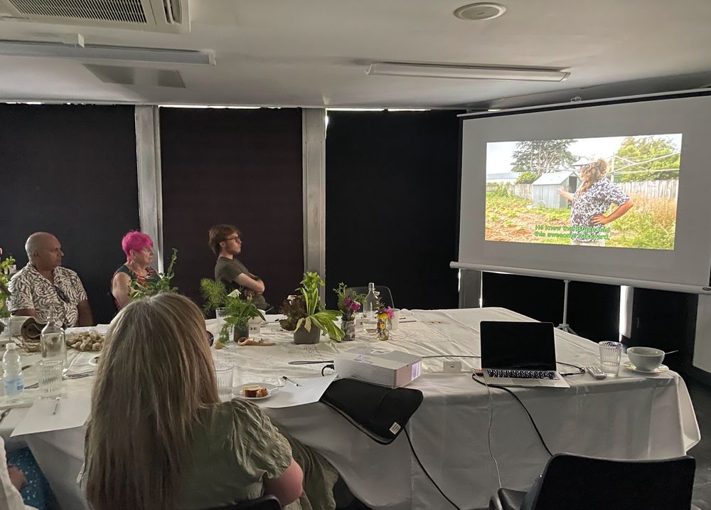 People sitting around a table and watching the short films on screen.